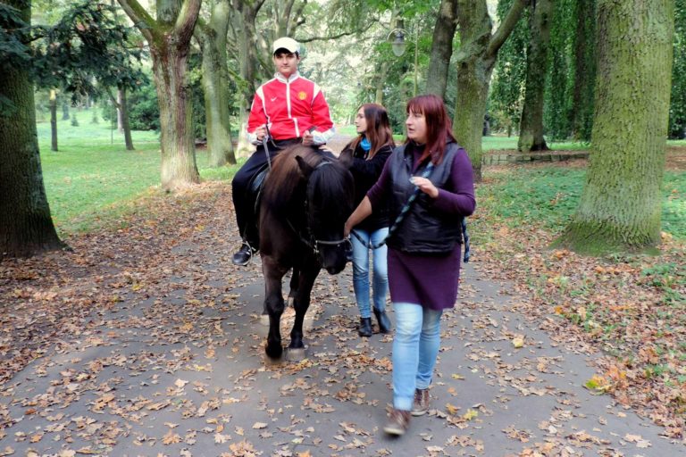 koń prowadzony przez 2 terapeutki - na koniu siedzi chłopiec